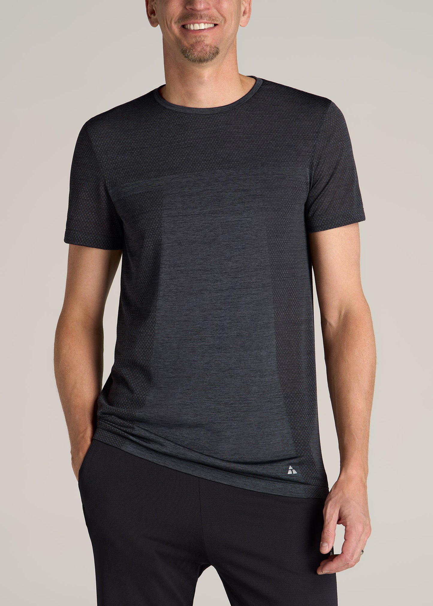 A tall man wearing American Tall's A.T. Performance MODERN-FIT Engineered Athletic Tall Tee in Charcoal Mix