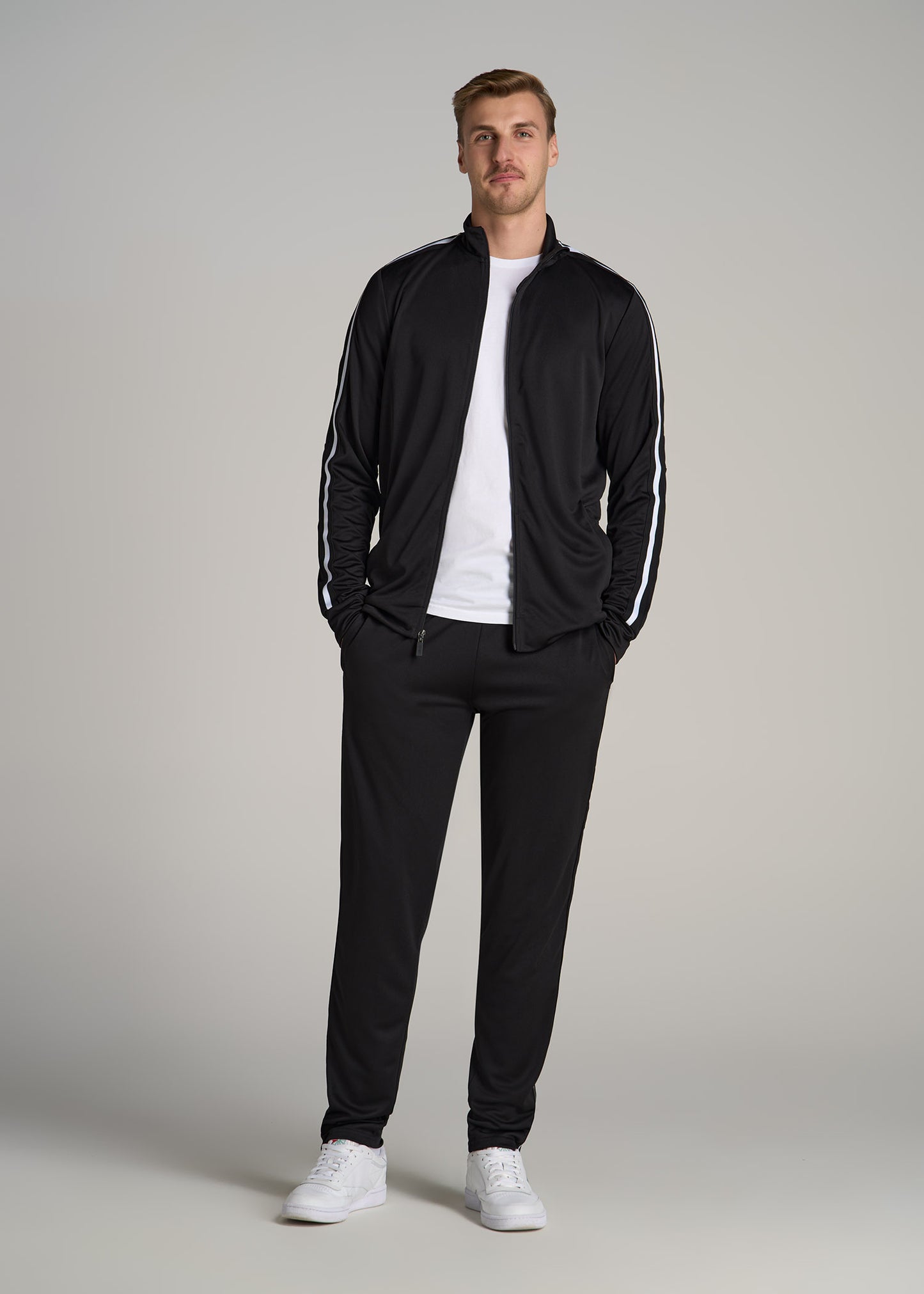 A tall man wearing American Tall's Athletic Stripe Tall Men's Jacket in Black-White Stripe