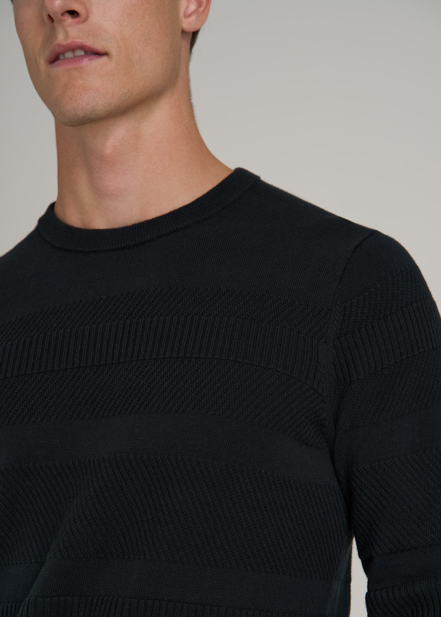 A closeup of a tall man wearing American Tall's Minimalist Embossed Knit Sweater for Tall Men in Midnight Green