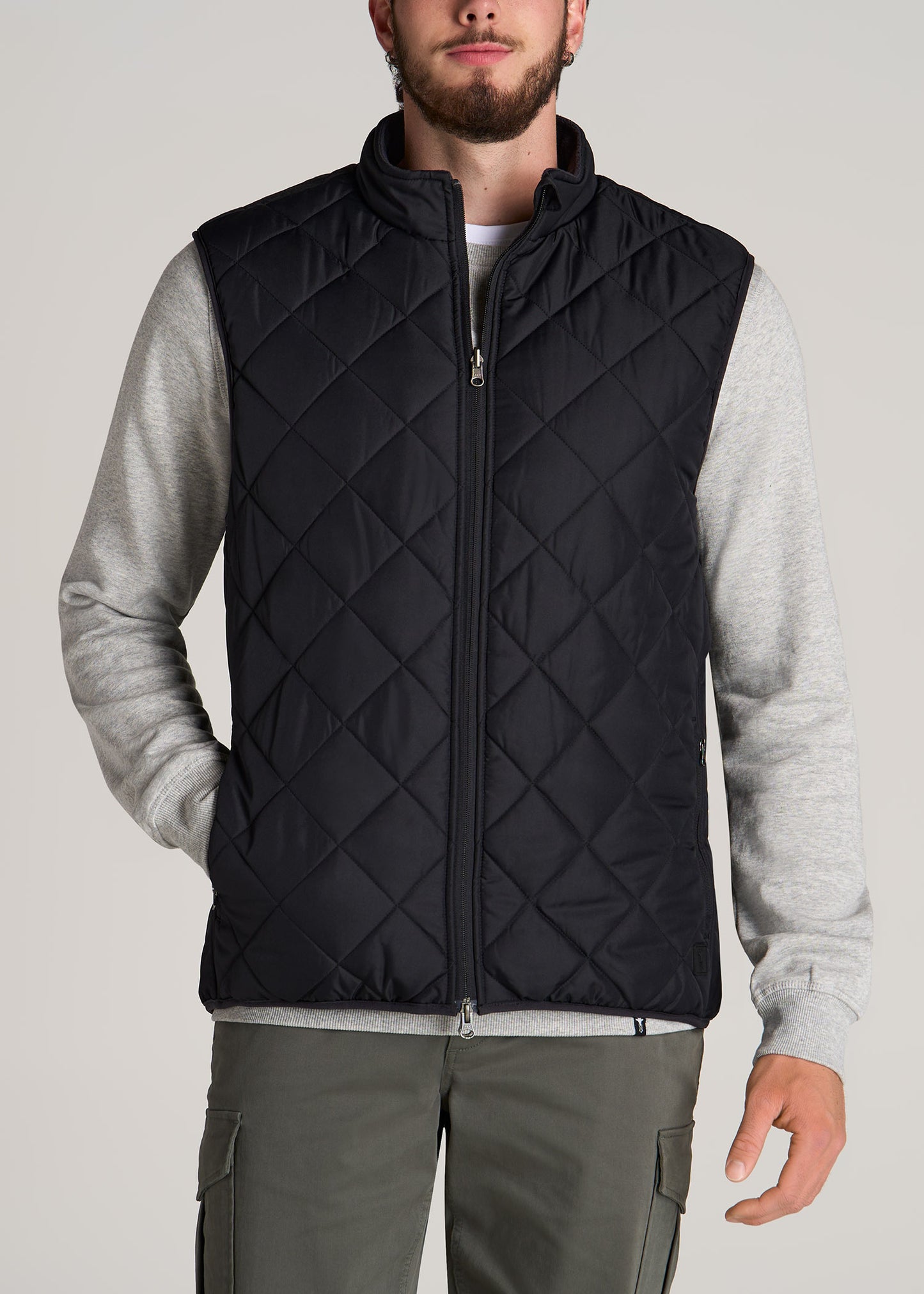 A tall man wearing American Tall's Quilted Reversible Tall Men's Vest in Black & Charcoal