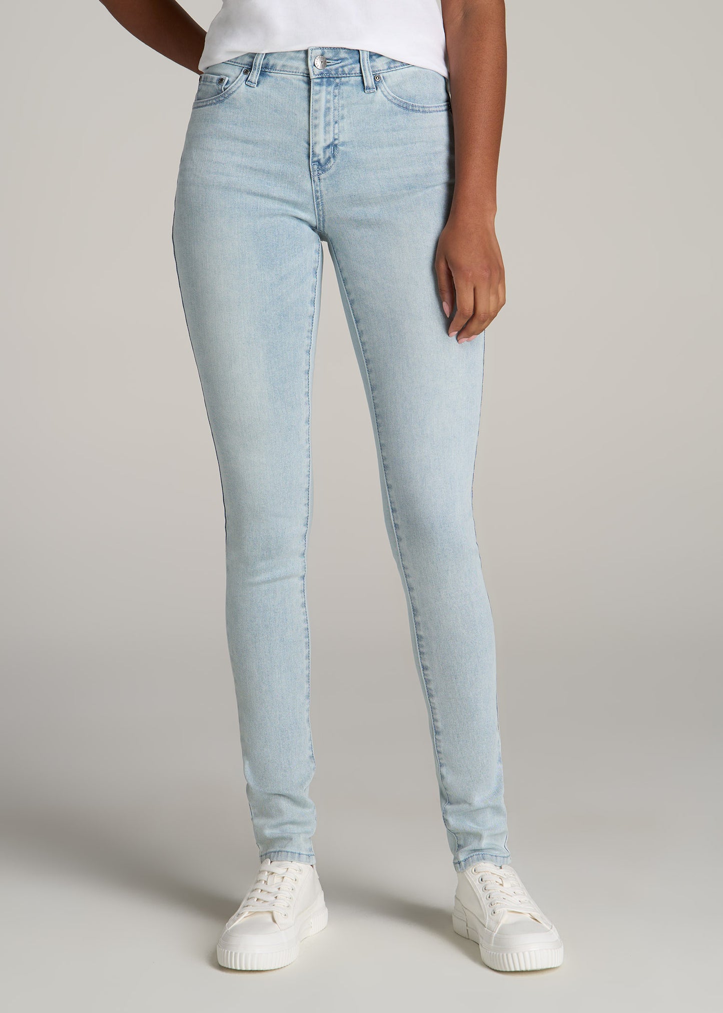 Tall woman wearing American Tall's Sarah Mid-Rise Skinny Jean in the color Light Sunwashed Blue.