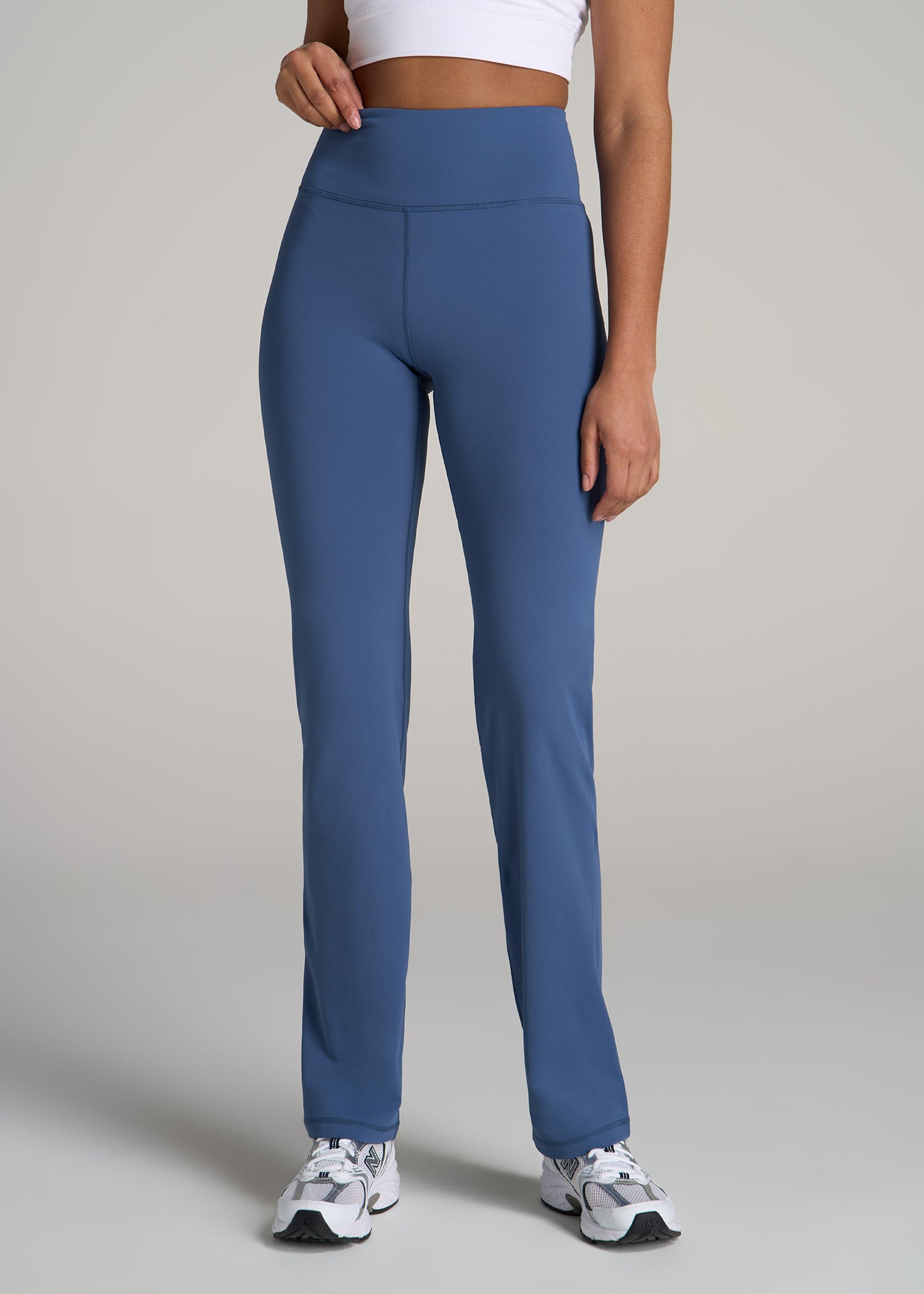 A tall woman wearing American Tall's Balance Straight Leg Leggings in Steel Blue.