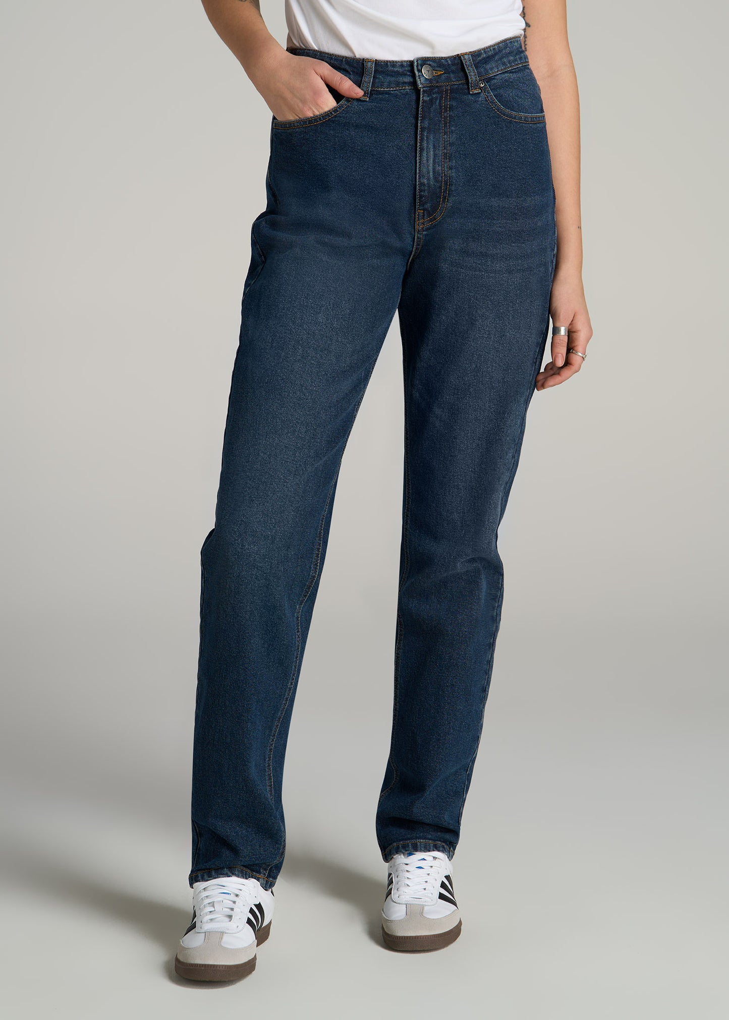 A tall woman wearing American Tall's Emma High Rise Relaxed Tapered Tall Women's Jeans in Faded Dark Indigo