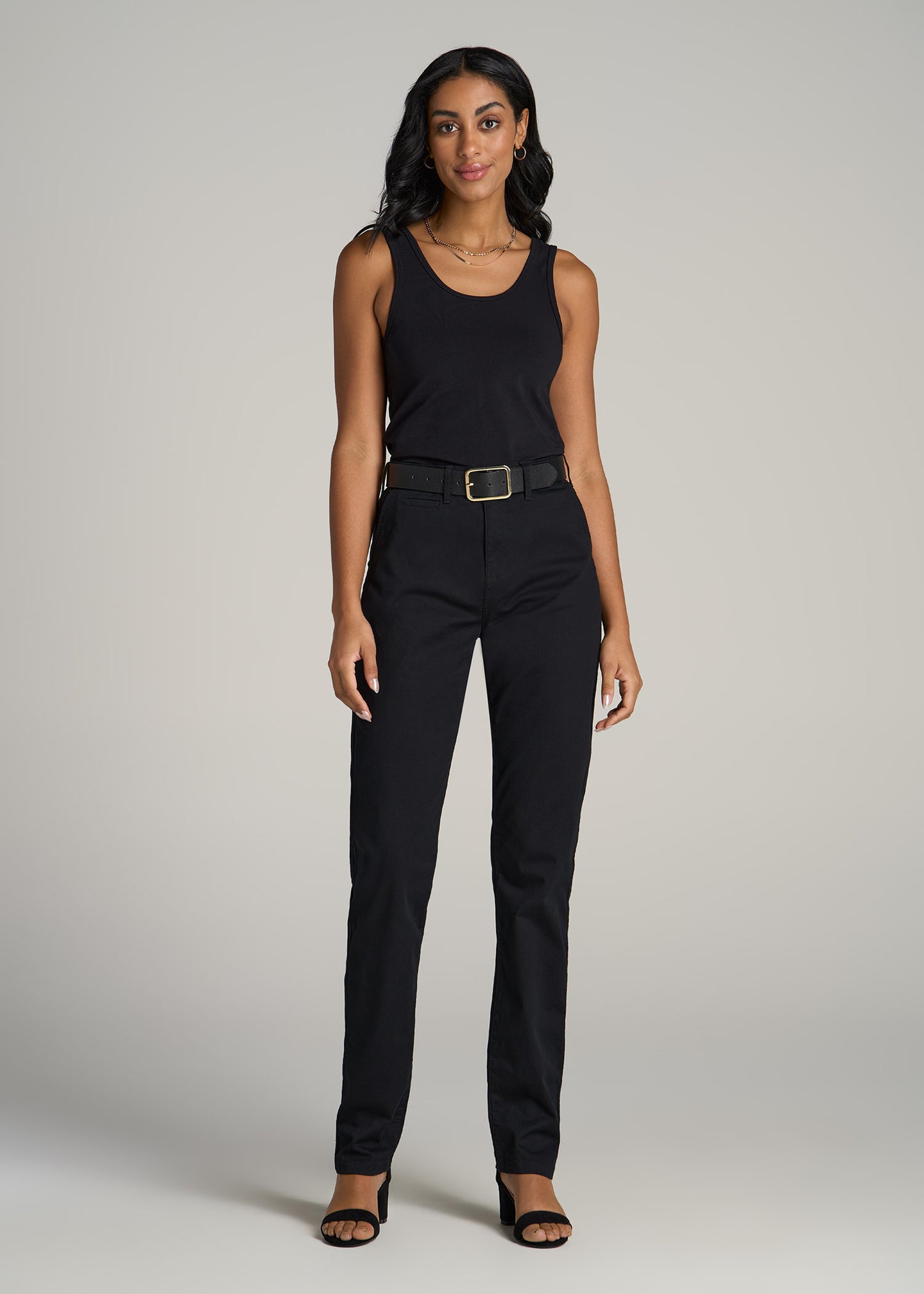 A tall woman wearing American Tall's High Rise Tapered Chino Pants for Tall Women in Washed Black with a black tank top.