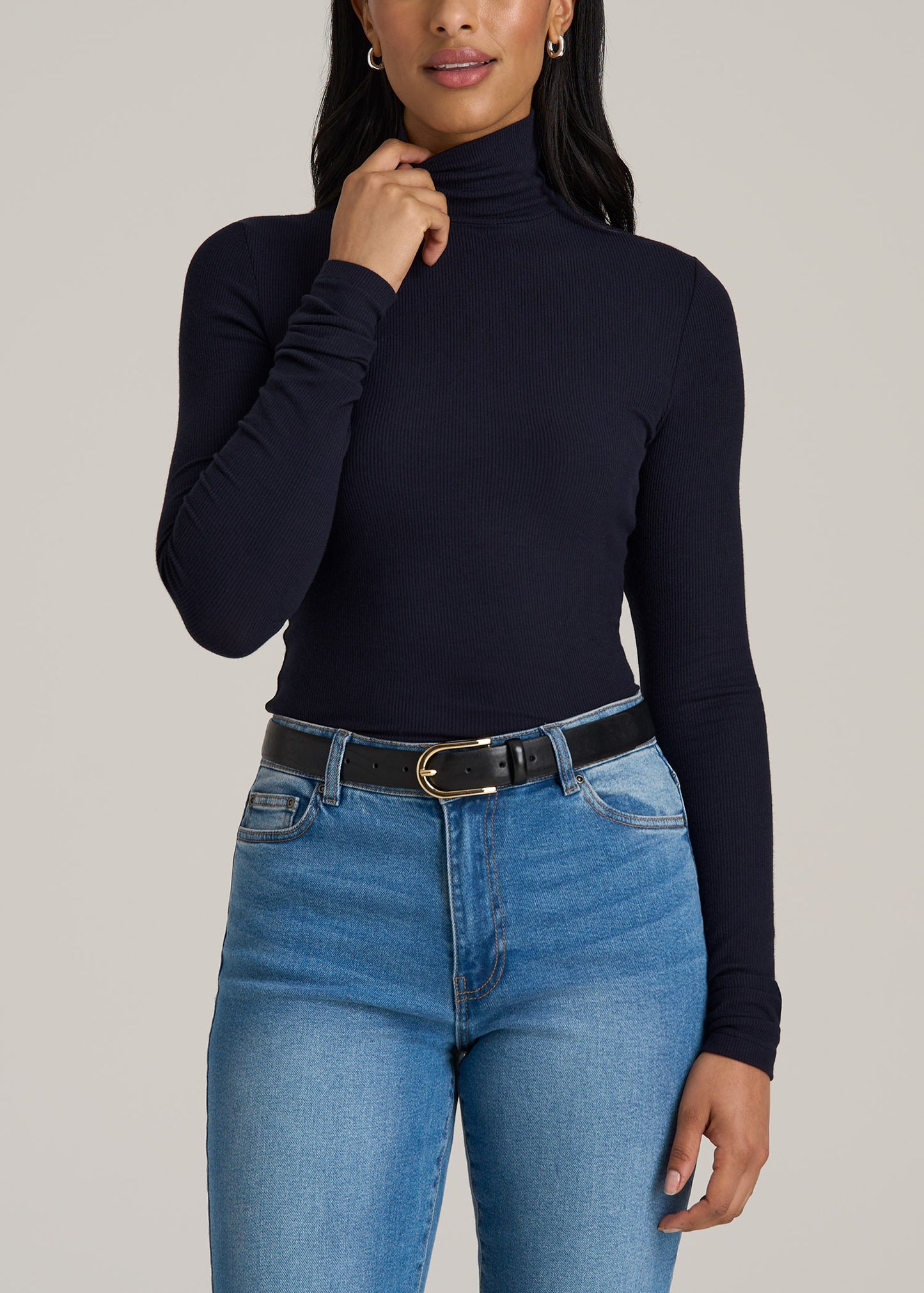 A tall woman wearing American Tall's Tall Women's FITTED Long Sleeve Ribbed Turtleneck Tee in Deep Navy