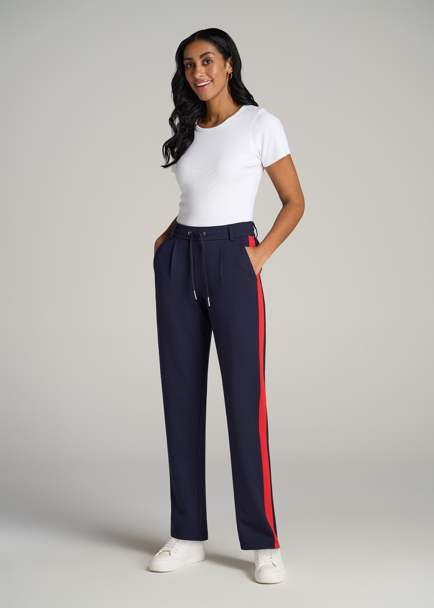 A tall woman wearing American Tall's Pull On Tuxedo Stripe Pants for Tall Women in true navy and radiant red along with a white tee.