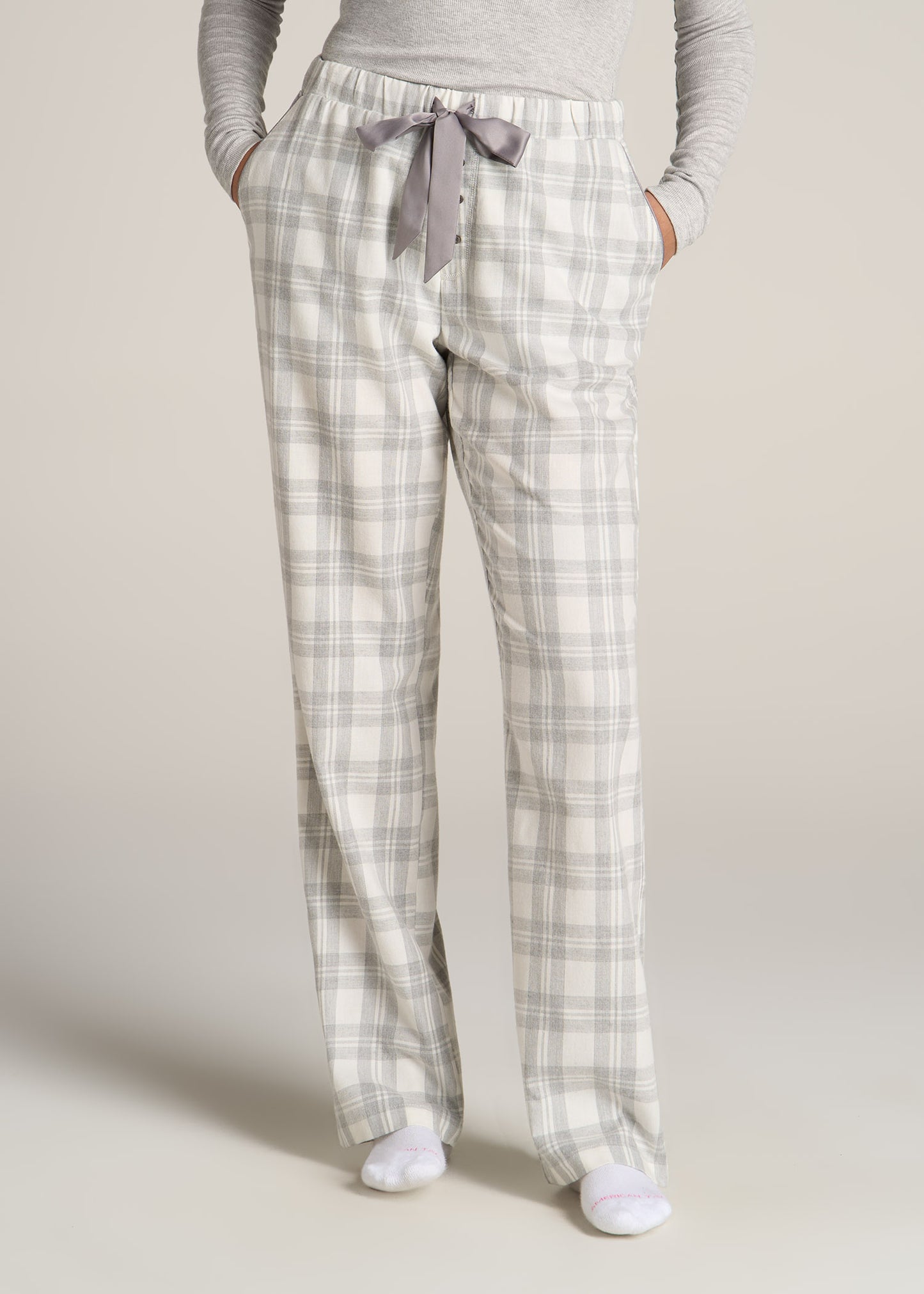 A tall woman wearing American Tall's Open-Bottom Flannel Women's Tall Pajama Pants in Heather Grey and White Plaid