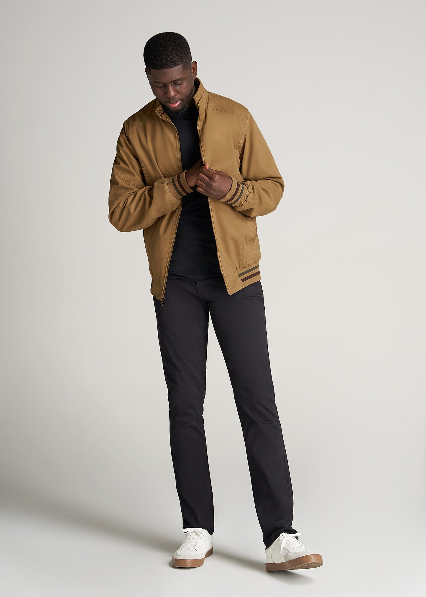 A tall man wearing American Tall's LJ&S Cotton Bomber Jackets for Tall Men in Sahara along with black pants and a black shirt.