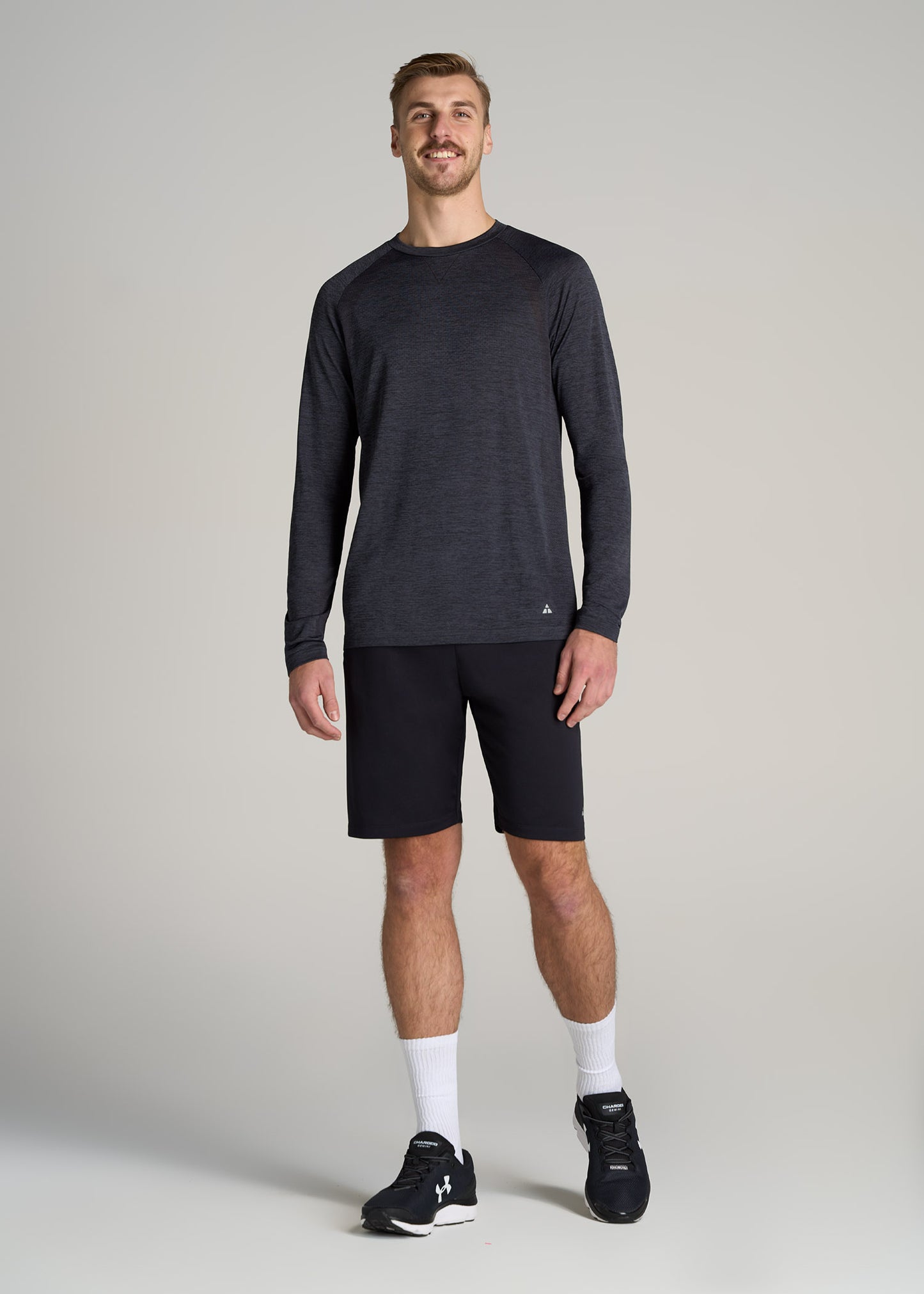 A tall man wearing American Tall's A.T. Performance MODERN-FIT Raglan Shirt for Tall Men in Charcoal Mix