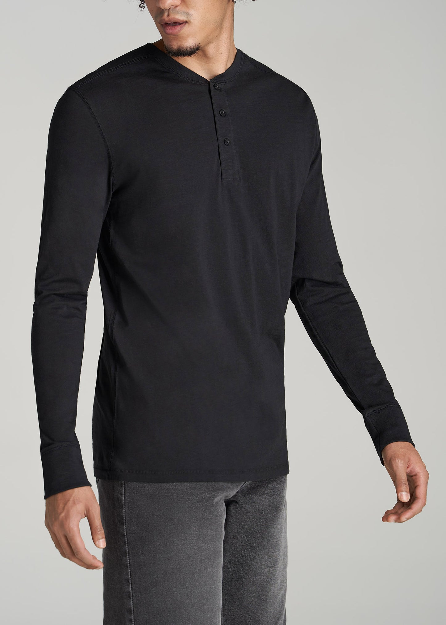 A tall man wearing American Tall's Men's Tall Three Button Long Sleeve Slub Henley in Black