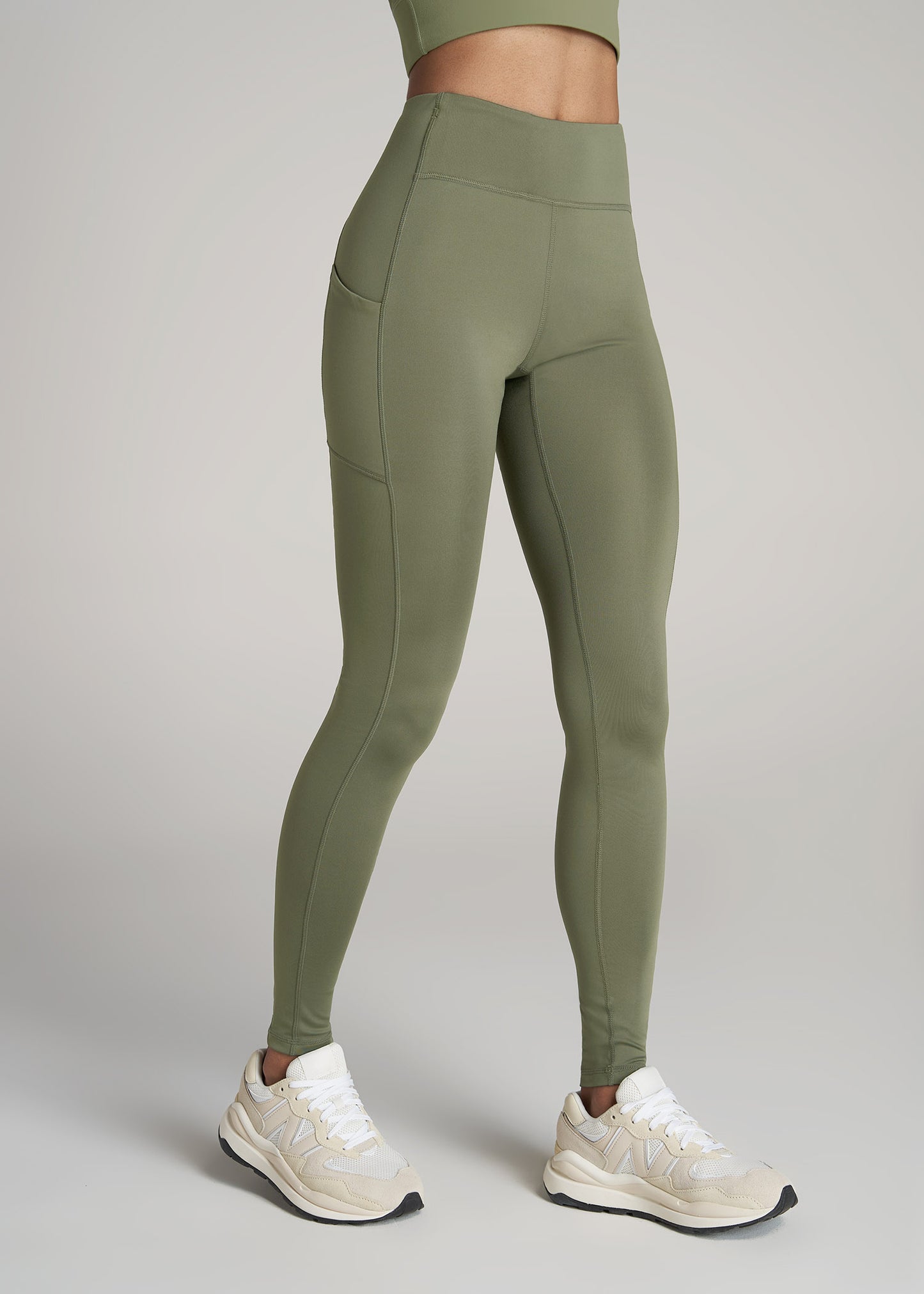 A tall woman wearing American Tall's Performance Leggings with Pocket in Olive.