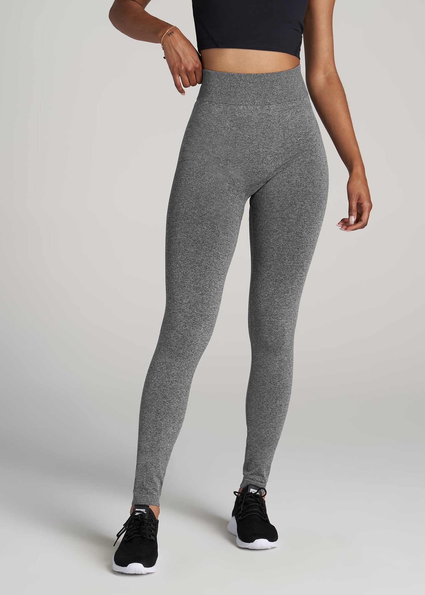 A tall woman wearing American Tall's Seamless Compression Legging in Black Grey Heather.