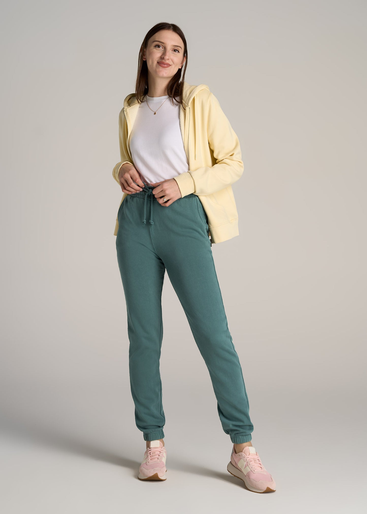 A tall woman wearing American Tall's Wearever Fleece SLIM-FIT High-Waisted Women's Garment Dye Sweatpants in Juniper Green